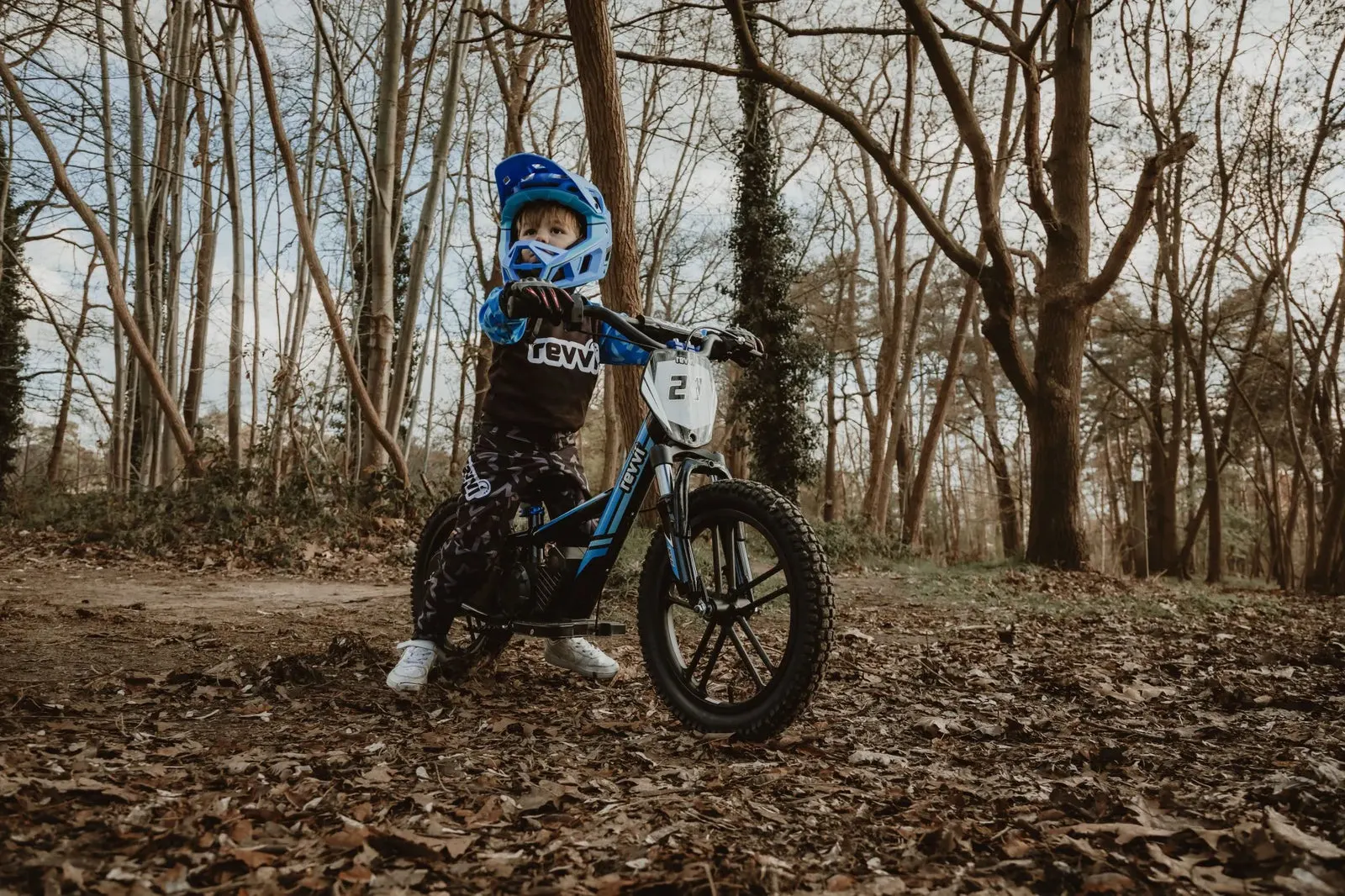 Young child riding a Revvi electric balance bike outdoors